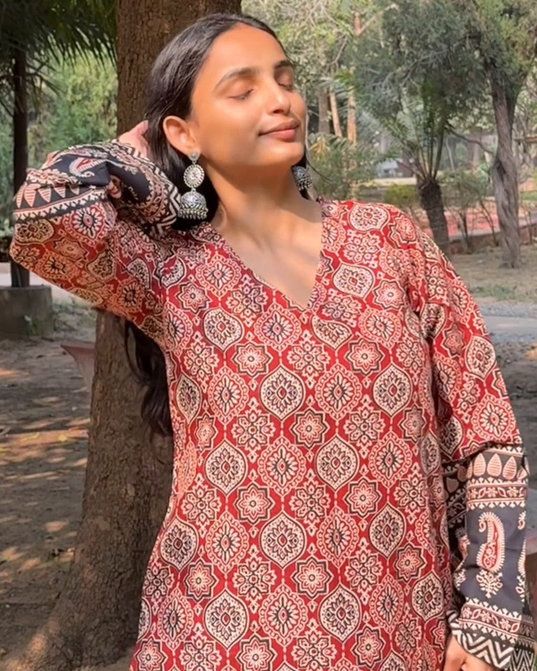 Woman wearing a patterned kurta standing outdoors with text overlay.