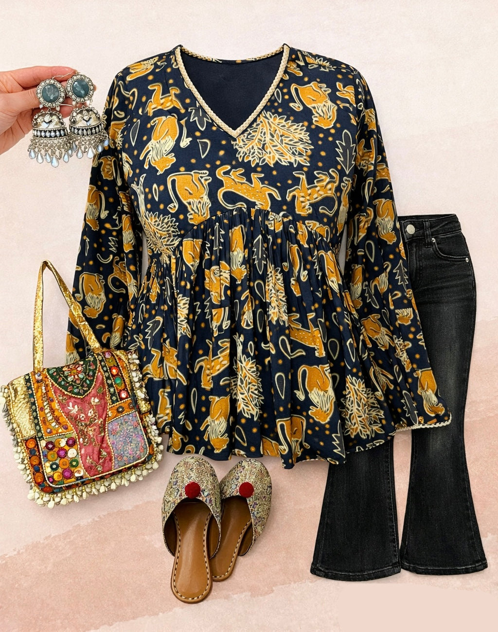 Navy blue patterned top with long sleeves, black pants, and decorative accessories on a beige background.