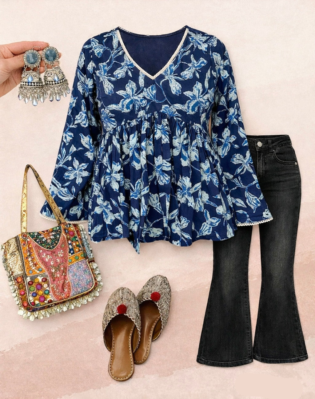 Navy floral blouse with black jeans, colorful bag, and decorative shoes on a light pink background.