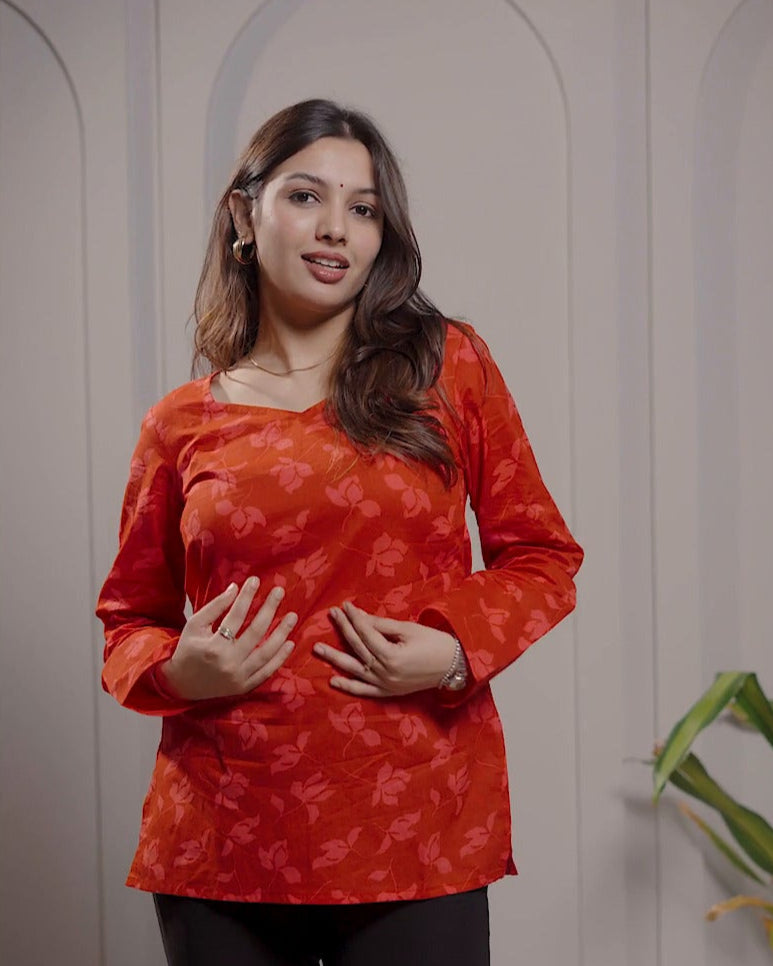 Woman wearing a red patterned top and black pants standing against a neutral background with text overlay.